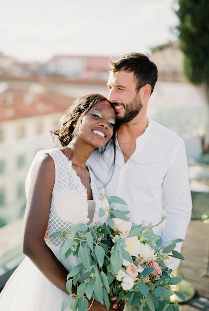 Bride with a bouquet put her head on the shoulder of the groom