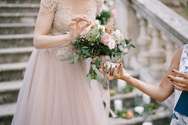 Bride with the bouquet takes a ring out of the box while standing on the steps