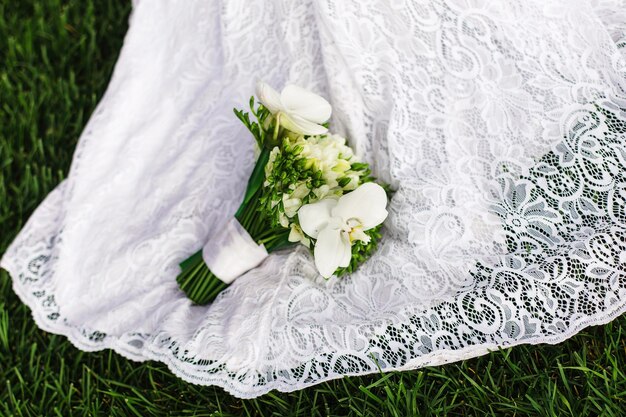 Photo bride with a bouquet of white orchid on the wedding dress