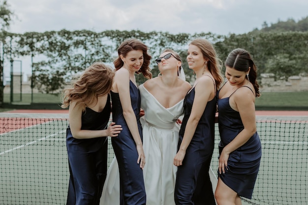 Sposa con le damigelle d'onore negli abiti scintillanti sul campo da tennis