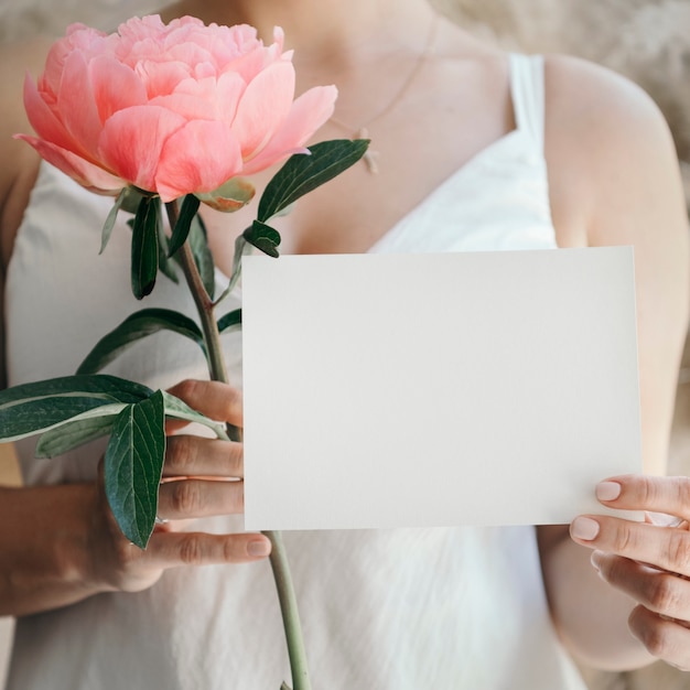 Photo bride with a coral sunset peony and a wedding invite