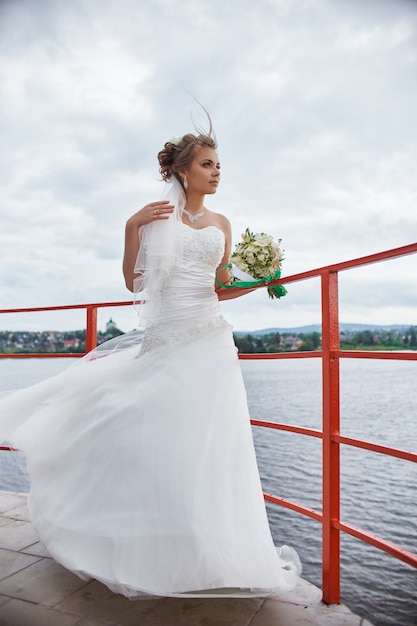 Bride with flowers in her hands standing in wind