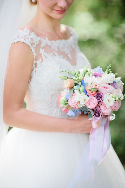 Bride with pink cheeks holds colorful wedding bouquet made of roses