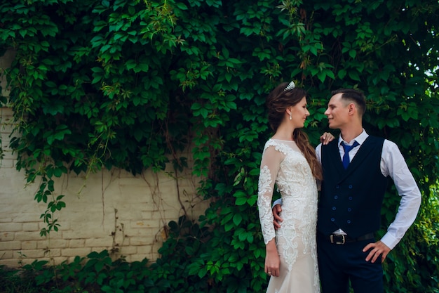 A bride with a short haircut and a stylish groom are walking in the park.