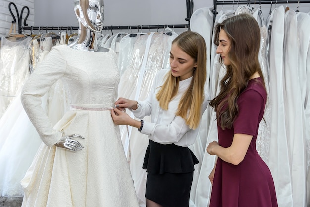 Bride with tailor choosing wedding dress in store