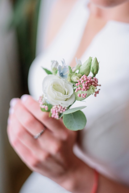 柔らかい腕を持つ花嫁は緑のboutonniereを保持する