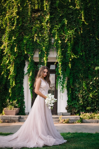 Sposa con un bouquet da sposa tra le mani in giardino