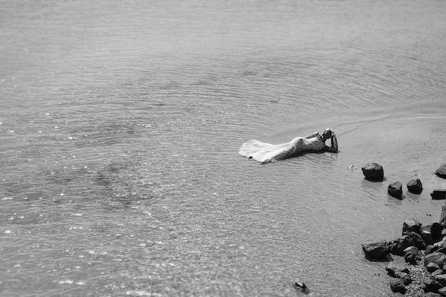 Bride or woman in wedding dress laying on sea beach