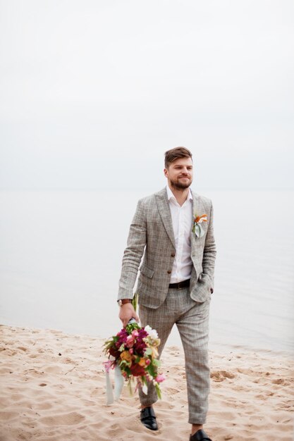 Photo bridegroom walking at beach against clear sky