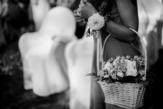 the brides hands tying the wedding wristband on the hand of the bridesmaid black and white photo