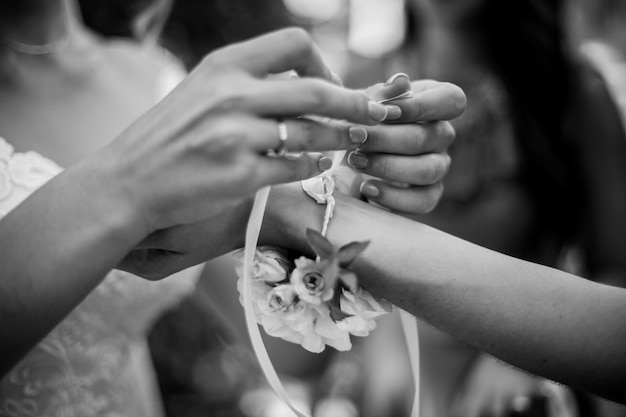 신부 들러리의 손에 결혼식 팔찌를 묶는 신부 손 흑백 사진