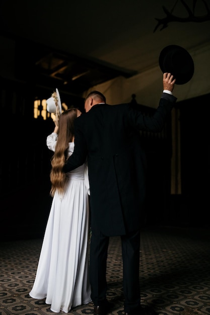 Brides hold hats in their hands young girl in a white wedding\
dress and hat with a bouquet of flowers the bride and groom go and\
hold an umbrella brides on the background of the castle