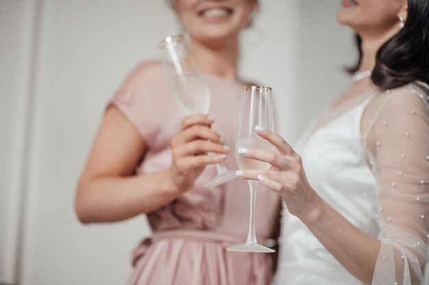 Photo bridesmaid and bride holding champagne flute