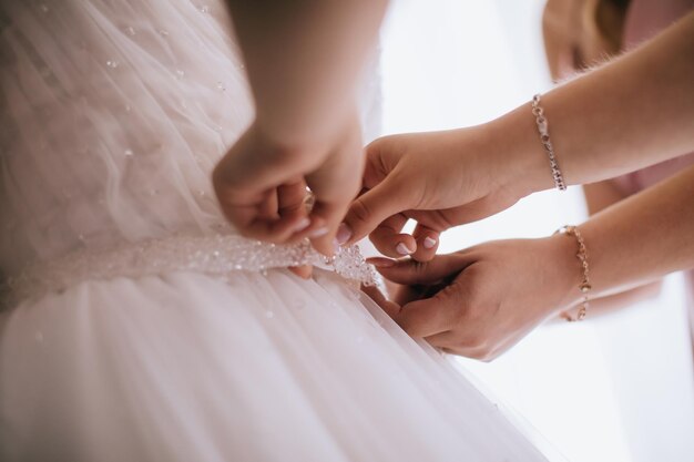 Bridesmaid Helping Bride With Dressing In Bedroom