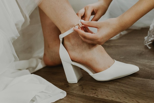 The bridesmaid helps the bride put on her shoes