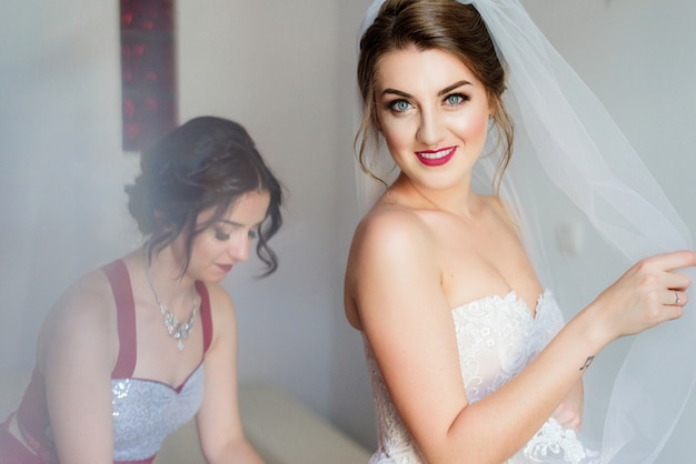 Bridesmaid helps bride to put on a wedding dress