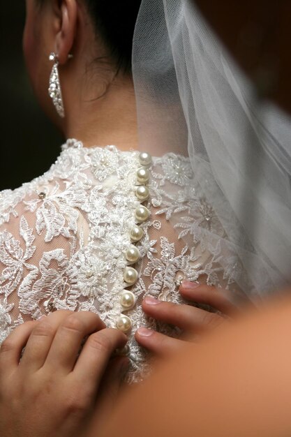 花嫁介添人は、花嫁のドレスのボタンを固定するのに役立ちます