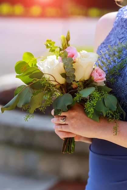 Bridesmaid holds elegance bouquet with green leaves and roses