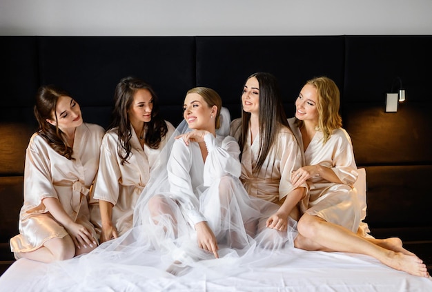 Bridesmaids greeting bride while sitting on bed