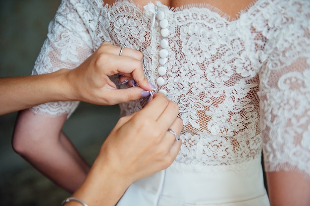 Bridesmaids helping to put a wedding lace dress