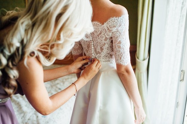 Bridesmaids helping to wear a wedding lace dress