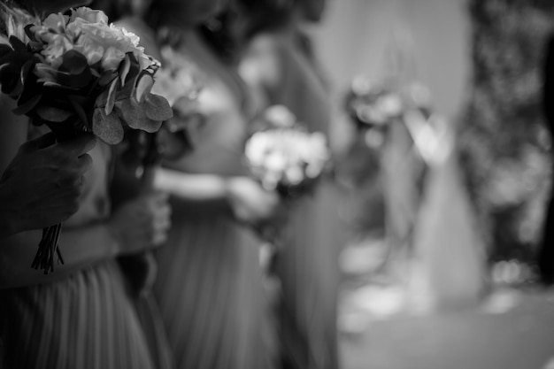 bridesmaids in pink dresses, holding bunches of flowers in their hands. black and white photo