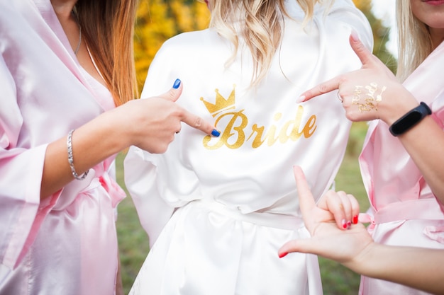 Bridesmaids show on the inscription on the dressing gown of the bride.