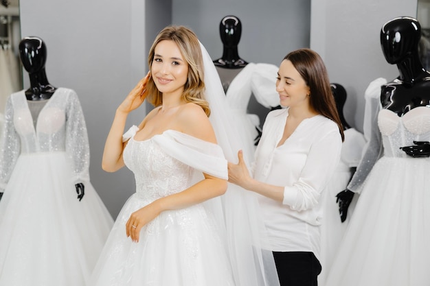 The bridetobe chooses a dress for the wedding A dressmaker's assistant is fitting a dress for the bride