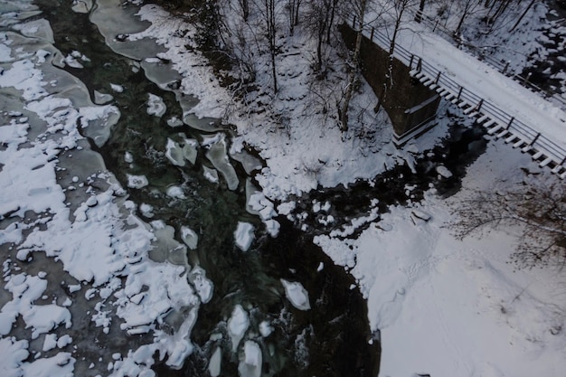 Мост через реку на фоне ледяных образований, покрытых снегом, вид сверху