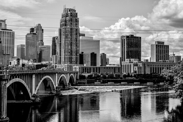 Photo bridge and buildings by river against sky in city