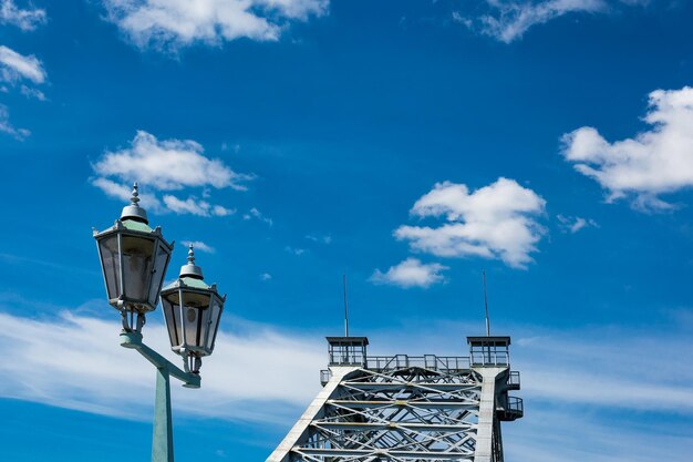 Bridge by lamp post against blue sky