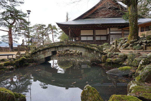 Photo bridge over lake by house and trees against sky