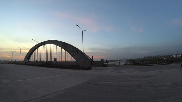 A bridge in the middle of a road with a sunset in the background.