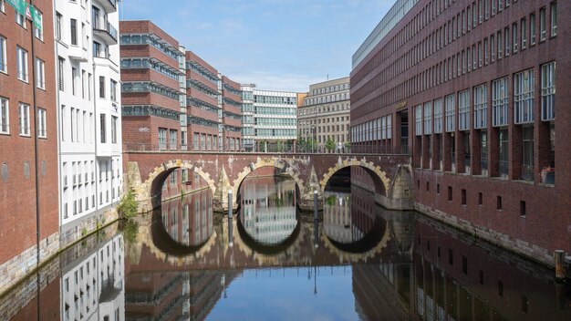 写真 空に照らされた街の建物に沿って運河を渡る橋