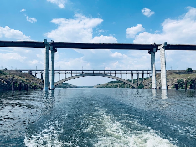 写真 雲の空に逆らって川を渡る橋