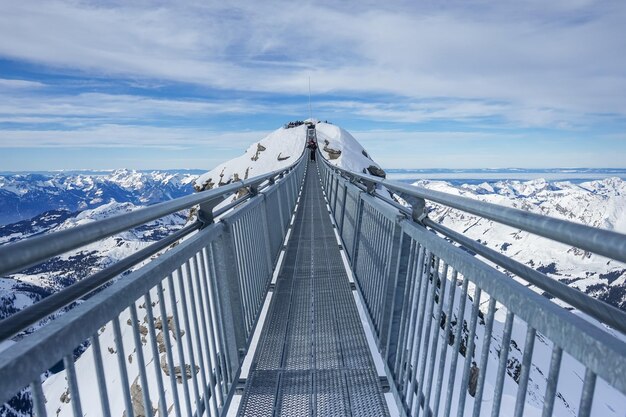 写真 空に逆らって雪に覆われた山を越えた橋