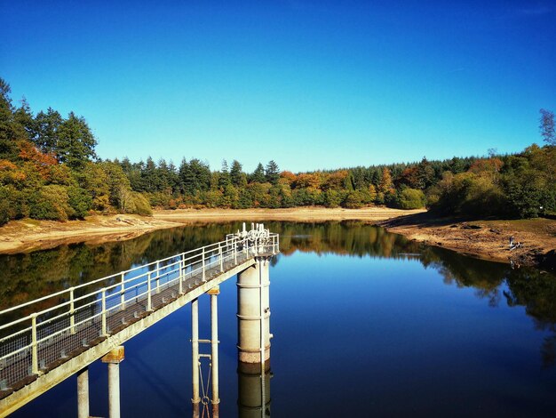 Photo bridge over river against clear blue sky