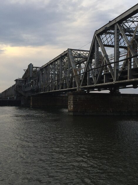 Bridge over river against cloudy sky