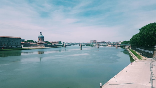 Photo bridge over river against cloudy sky