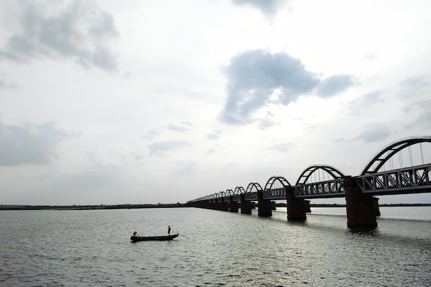 Photo bridge over river against cloudy sky