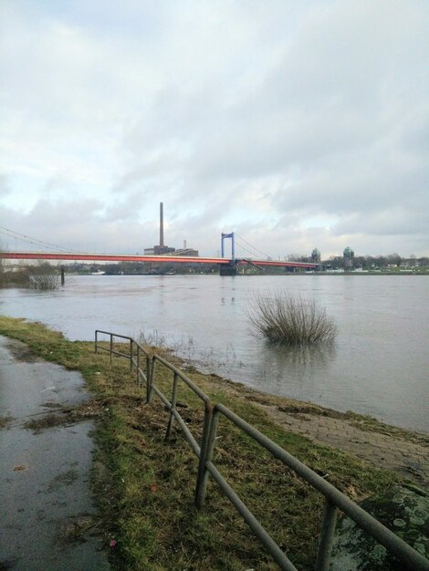 Bridge over river against cloudy sky