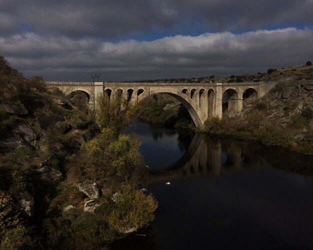 Photo bridge over river against cloudy sky