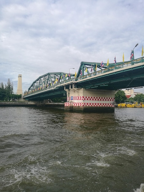 Bridge over river against cloudy sky