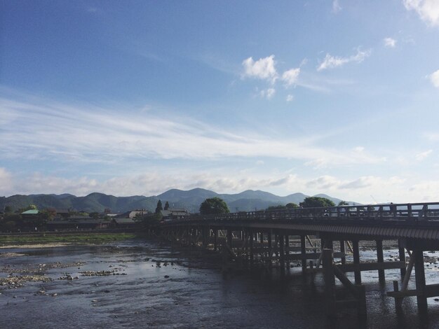 Bridge over river against cloudy sky