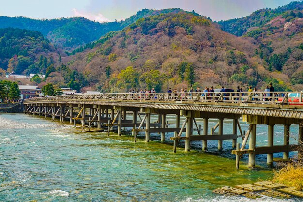 Photo bridge over river against mountain