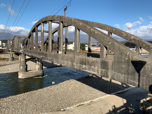 Bridge over river against sky in city