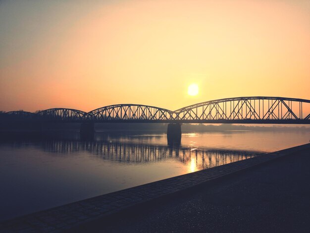 Bridge over river against sky during sunset