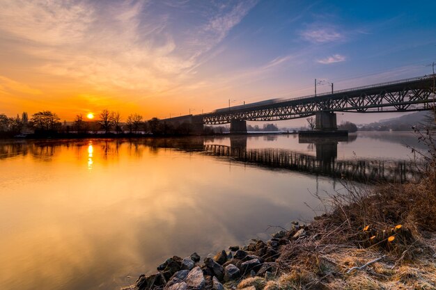 Bridge over river against sky during sunset