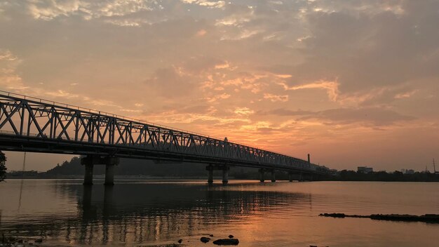 Photo bridge over river against sky during sunset