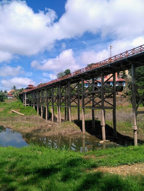 Bridge over river amidst field against sky